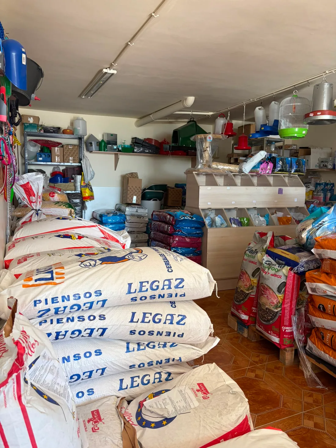 Sacos de pienso Legaz apilados junto a la pared de correas y collares